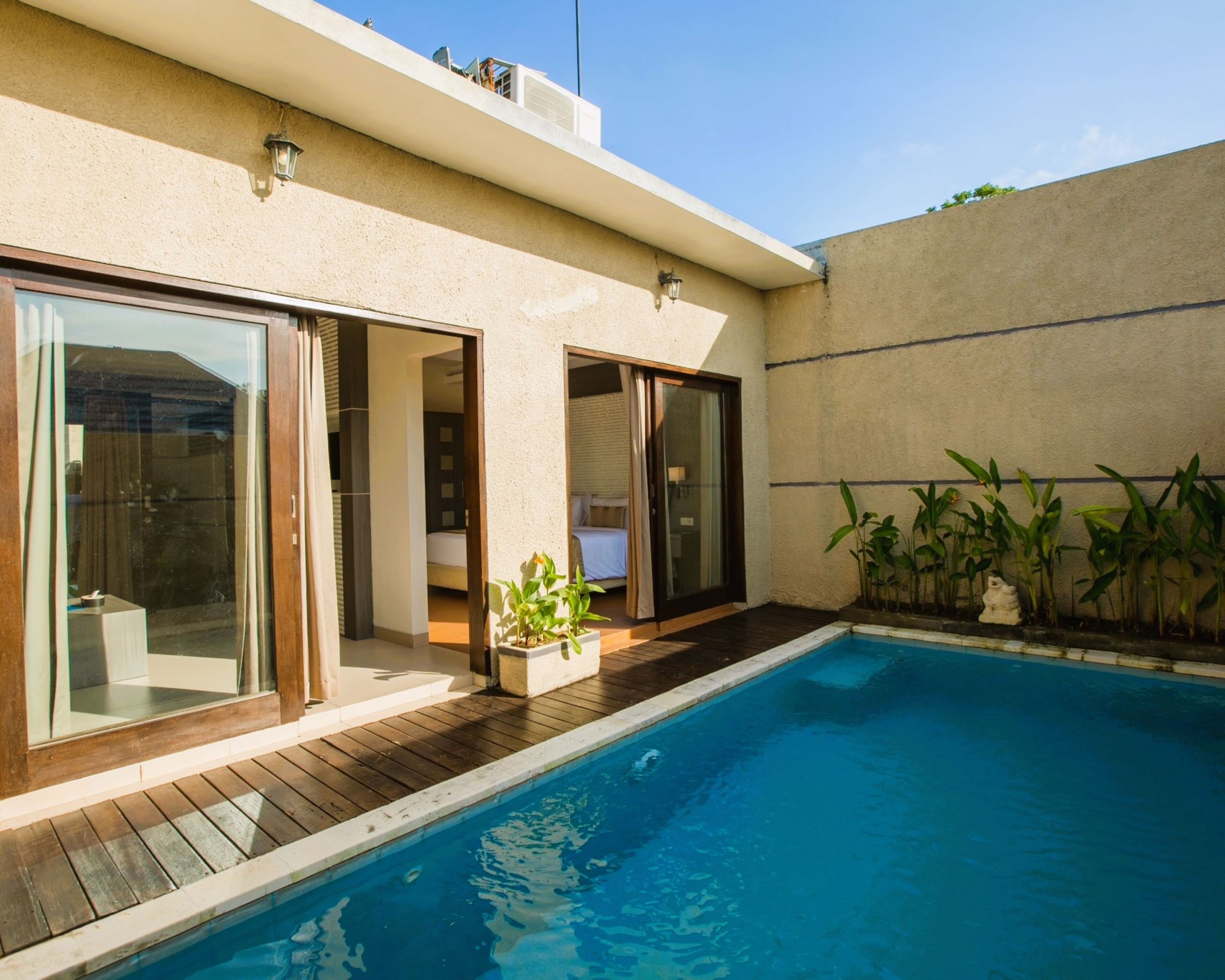 A modern house with a swimming pool, sliding glass doors, and a small garden area.