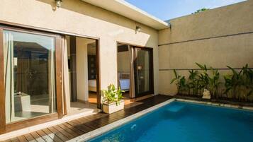 A modern house with a swimming pool, sliding glass doors, and a small garden area.