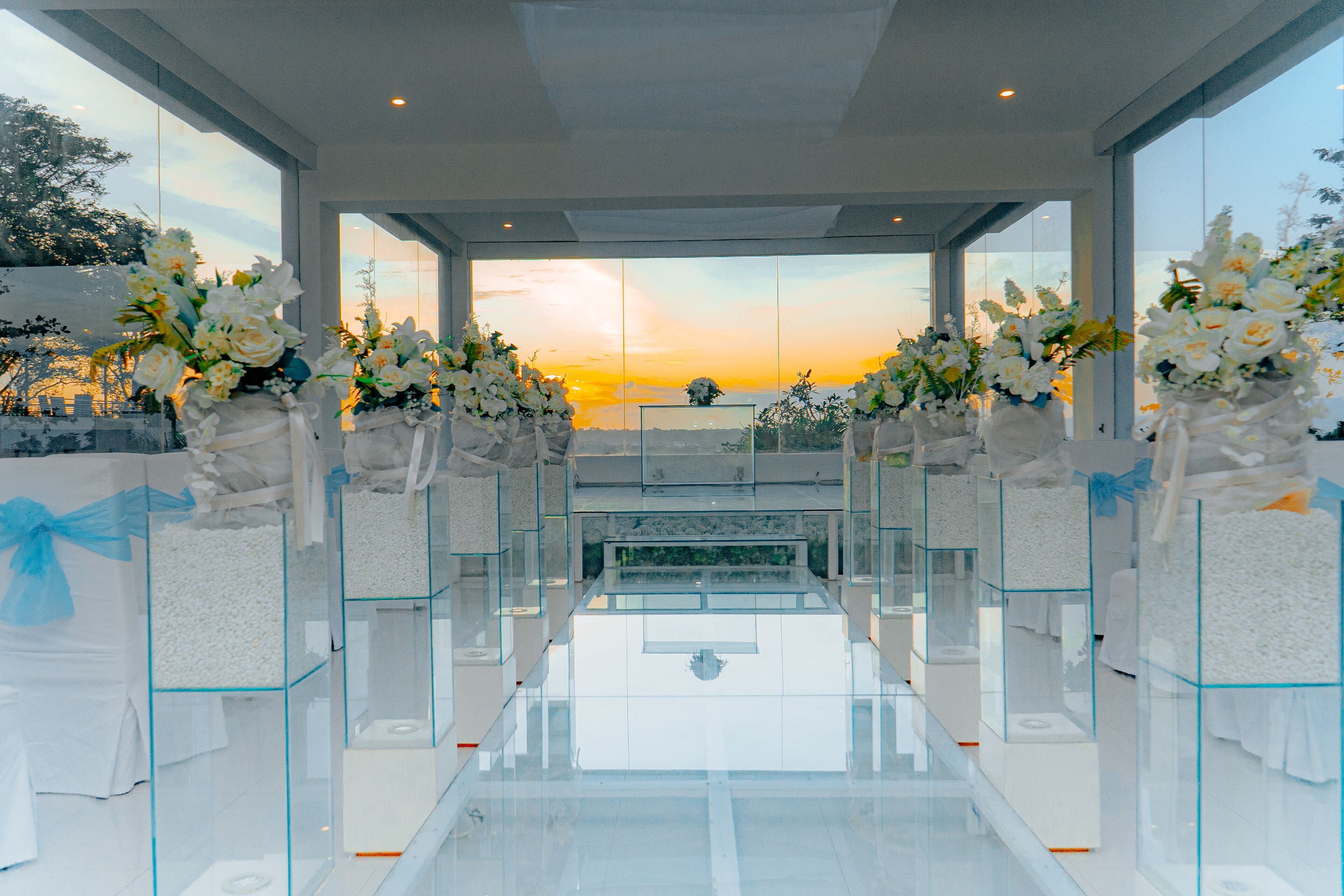 A modern interior with a glass partition and white floral arrangements.