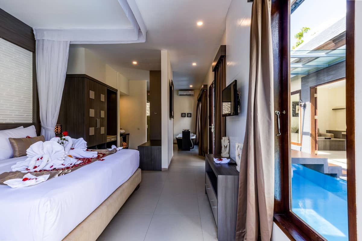 Une chambre d’hôtel avec un grand lit, un bureau, une vue sur une piscine, et une salle de bain avec douche et toilettes.