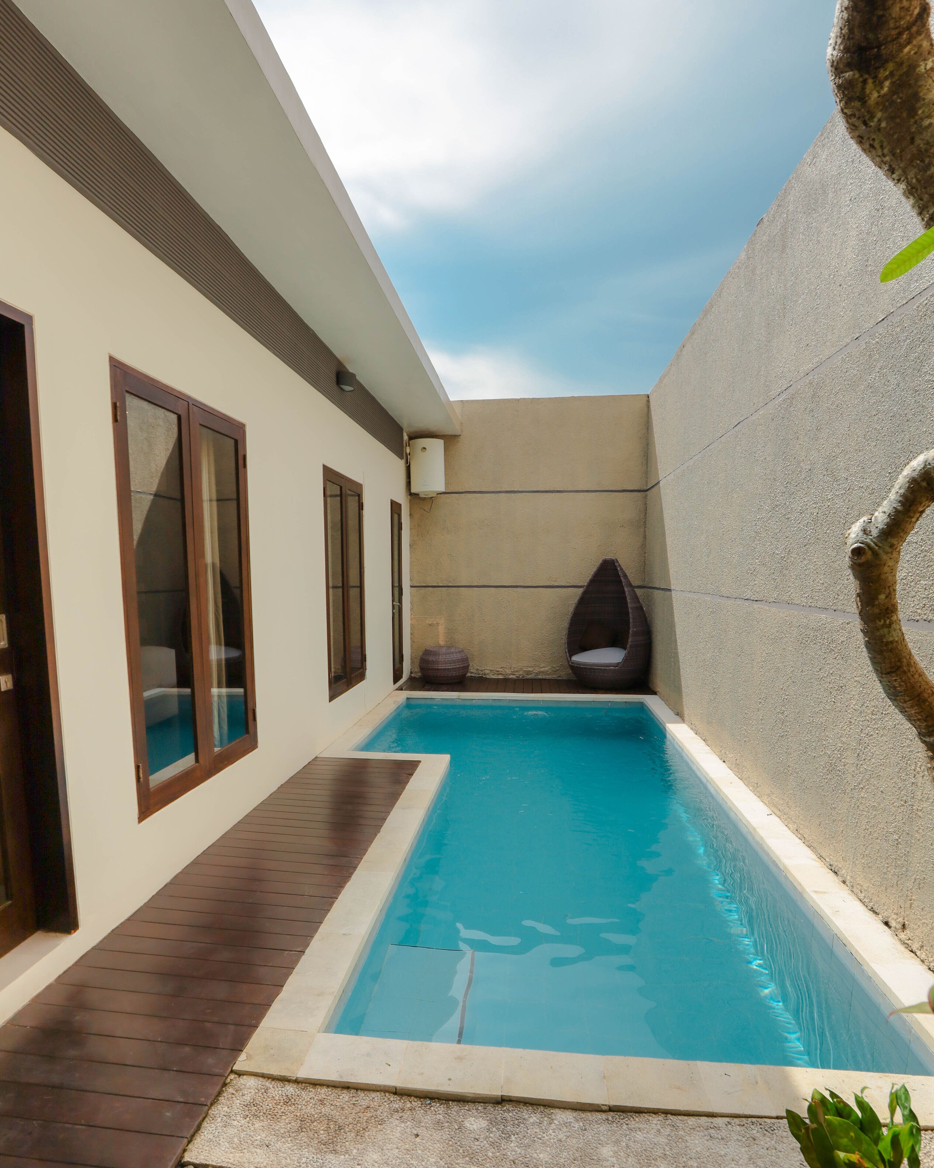 Una piscina con cubierta de madera, pared de concreto y ventana con vista al cielo.
