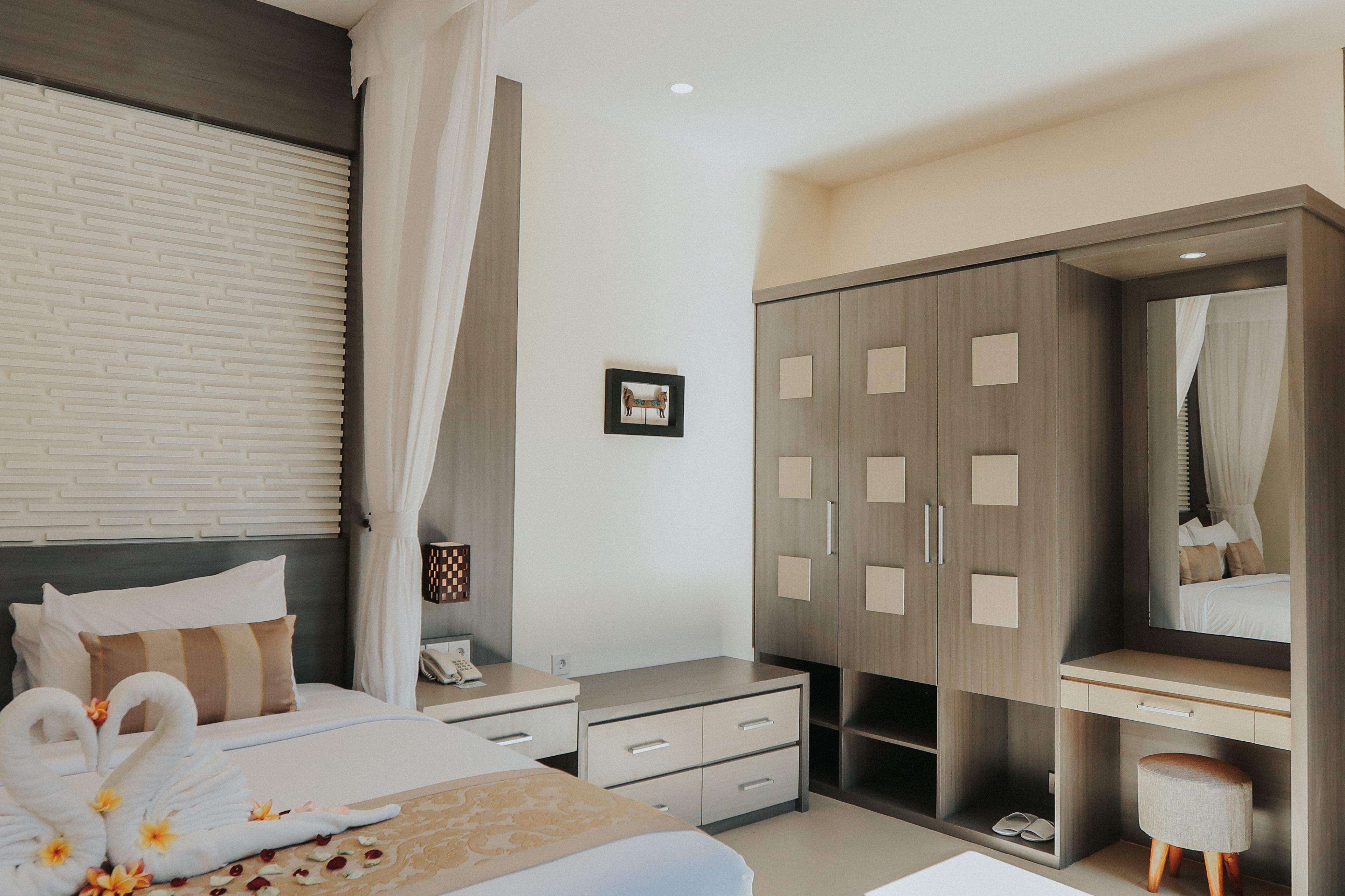 A modern bedroom with a bed, a vanity with a mirror, a wardrobe, and a bedside table.