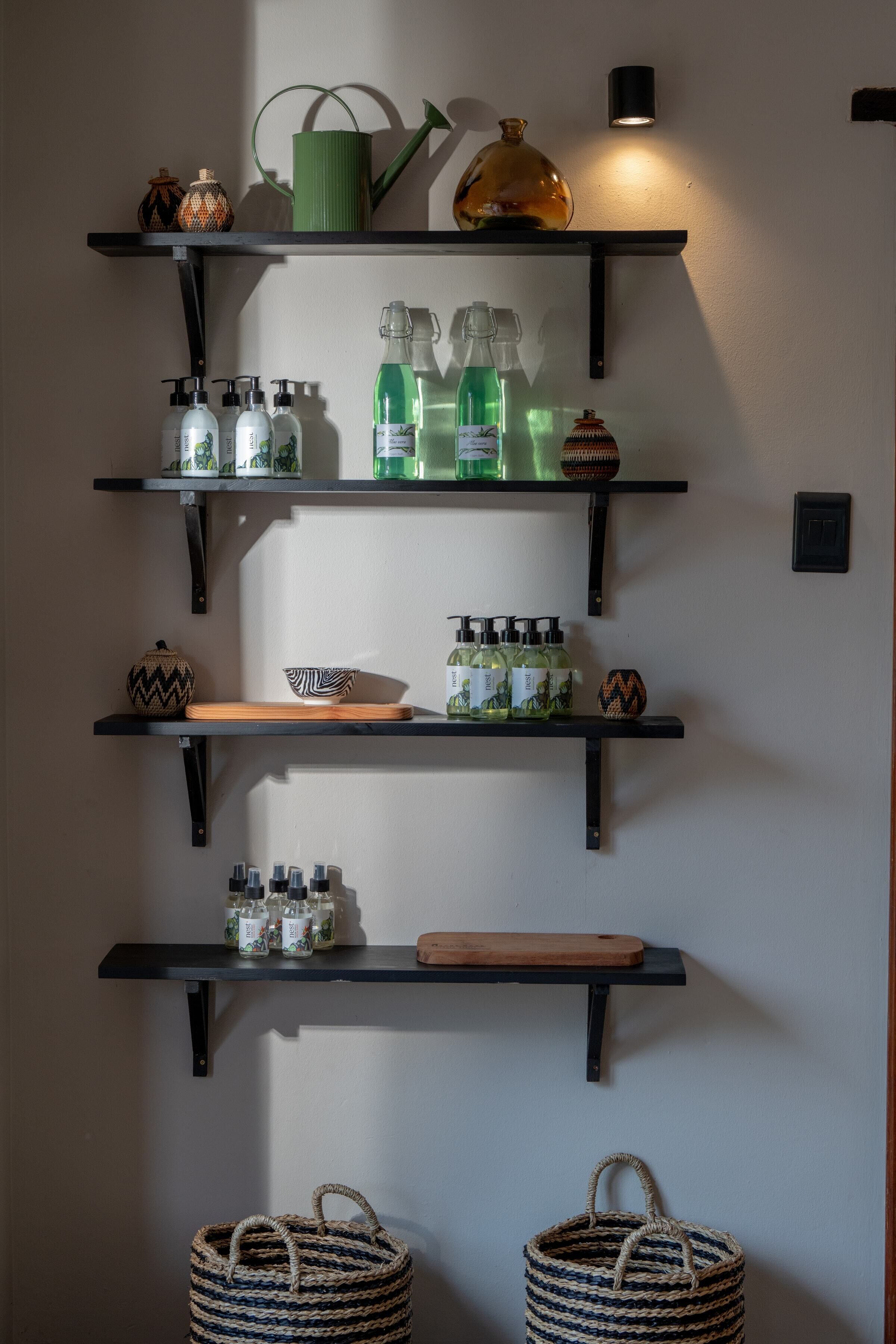 A wall with three black metal shelves holding various items.