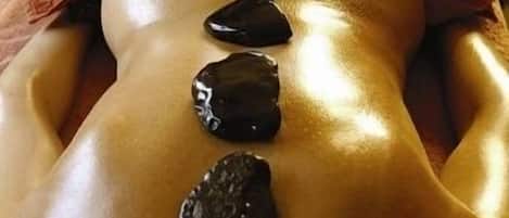 A person receiving a stone massage with three stones placed on their back.