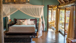 A bedroom with a canopy bed, a chandelier, and a view of the outdoors.