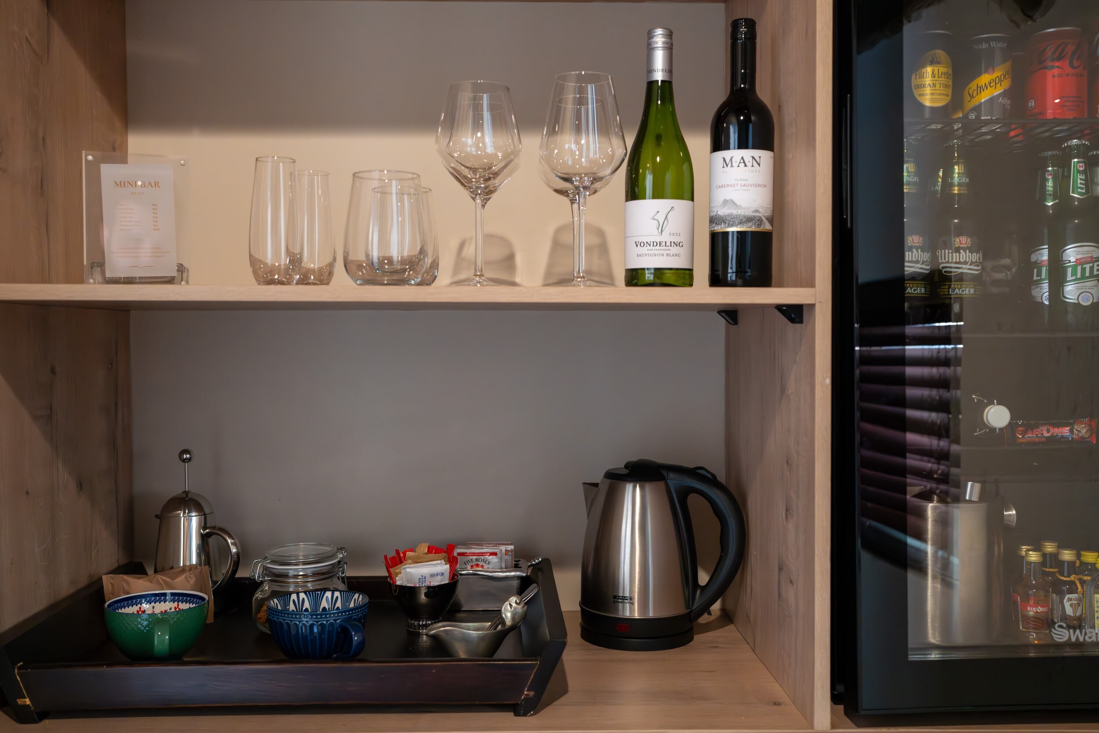 Un minibar con copas de vino, una botella de Vondeling y una selección de latas de cerveza.