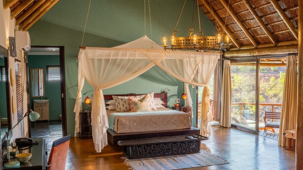 A spacious bedroom with a large bed, a canopy, and a view of the outdoors.