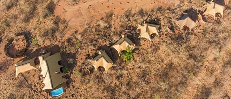 Vista aérea de um resort no deserto, com vários edifícios dispostos em linha, interligados por caminhos.
