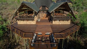 Un pavillon comprenant un bâtiment central et deux ailes, chacune dotée d’un espace extérieur aménagé et d’une façade en pierre.