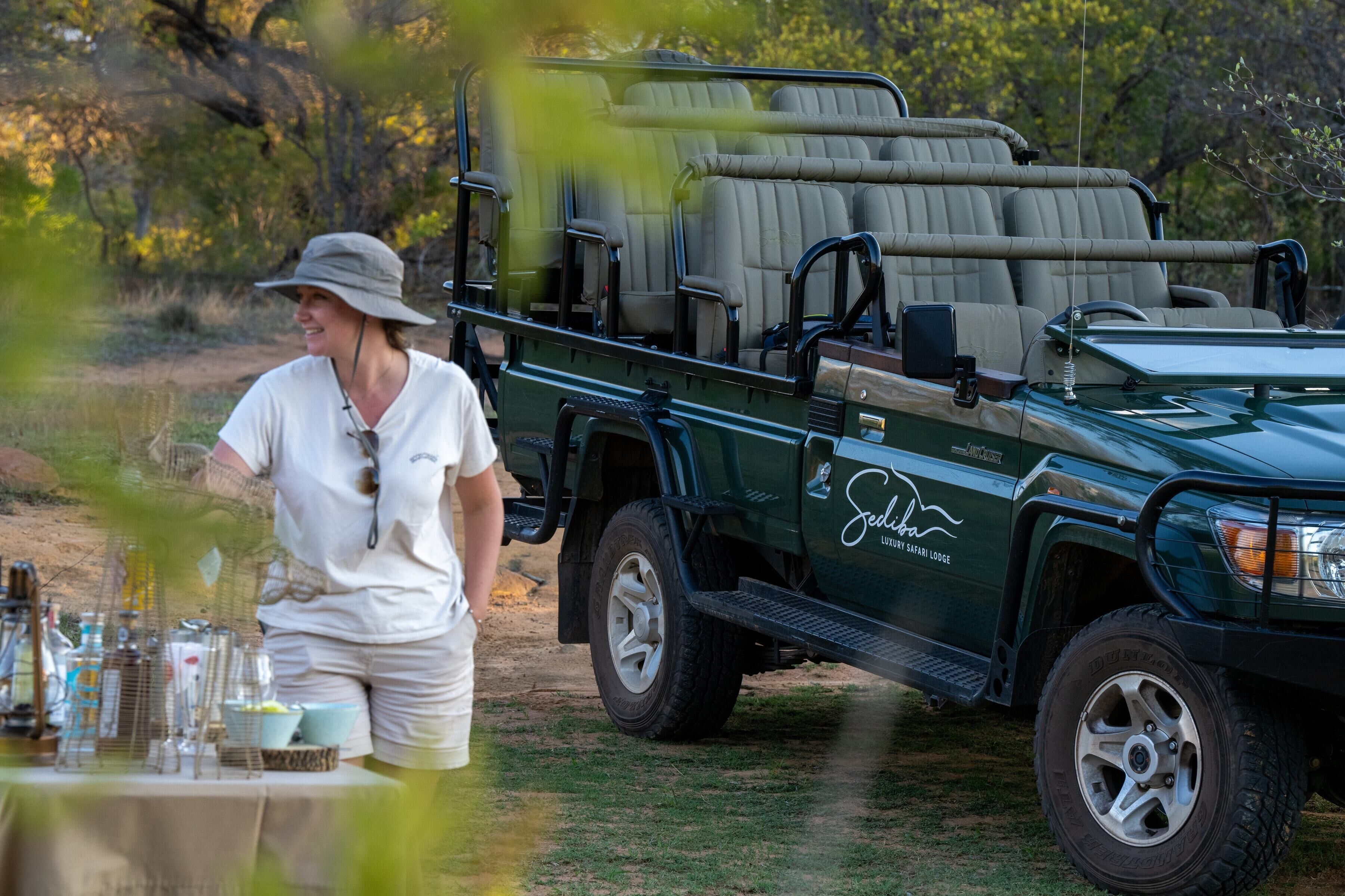 A safari lodge vehicle with a covered seating area and a table set with bottles and glasses.