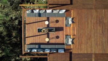 A wooden deck with a central seating area, surrounded by a wooden fence, and a view of the surrounding landscape.