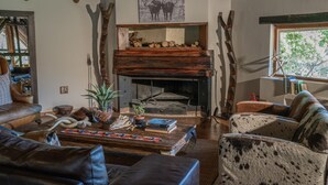 A rustic interior with a fireplace, leather furniture, and a bookshelf.