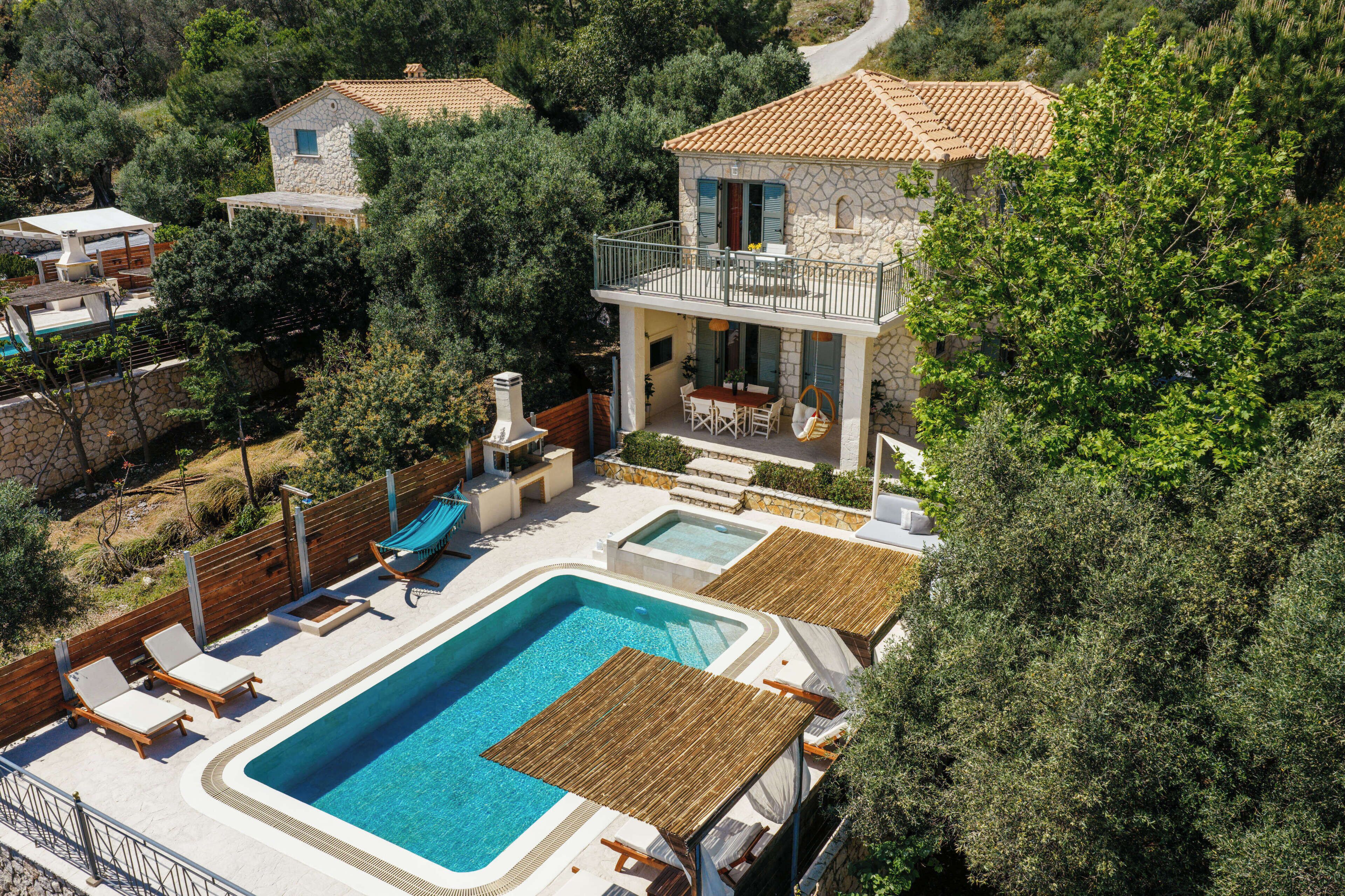 Una villa con piscina, mobiliario exterior y fachada de piedra.
