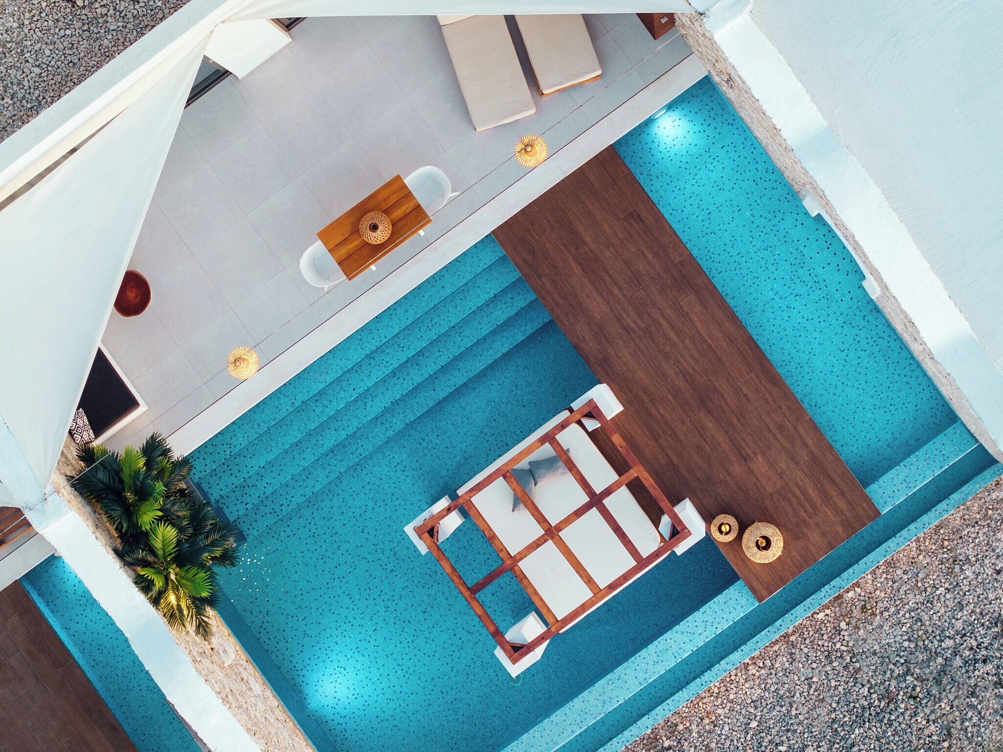 A top-down view of a modern hotel room with a pool, including a sun lounger, a small table, and a seating area.