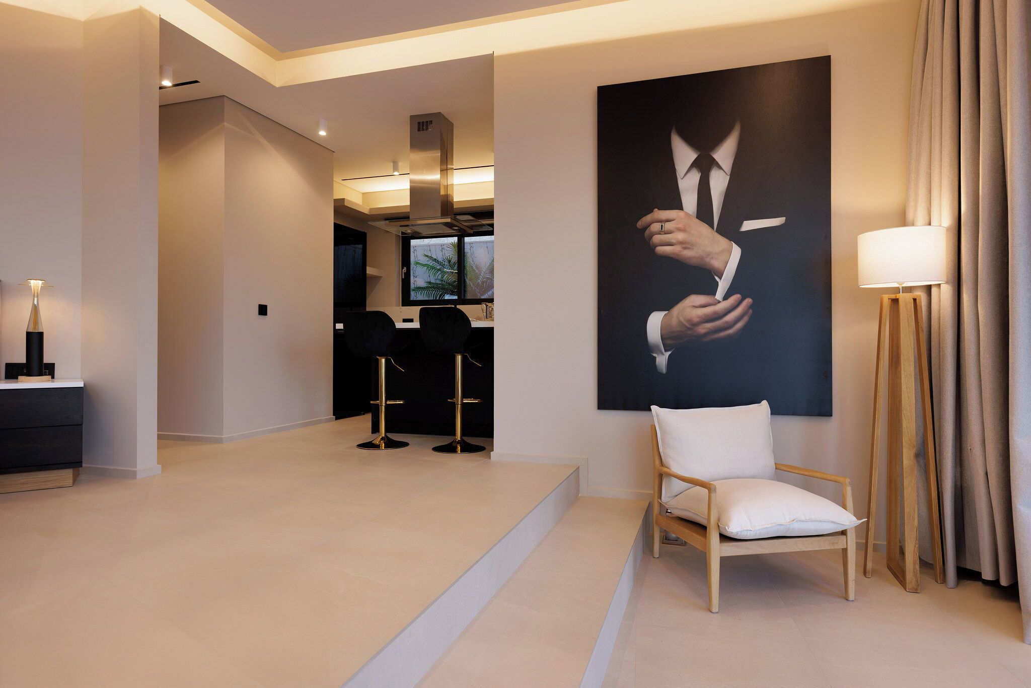 Een moderne hotellobby met een minimalistisch design, met een groot portret, een zithoek en een trap naar een andere ruimte.