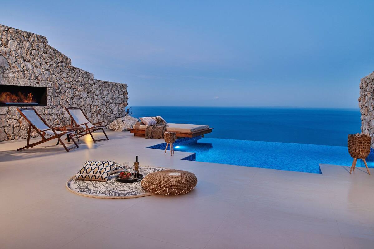 Un espace extérieur luxueux agrémenté d’un mur en pierre, d’un fauteuil de relaxation, d’un canapé et d’une petite piscine.