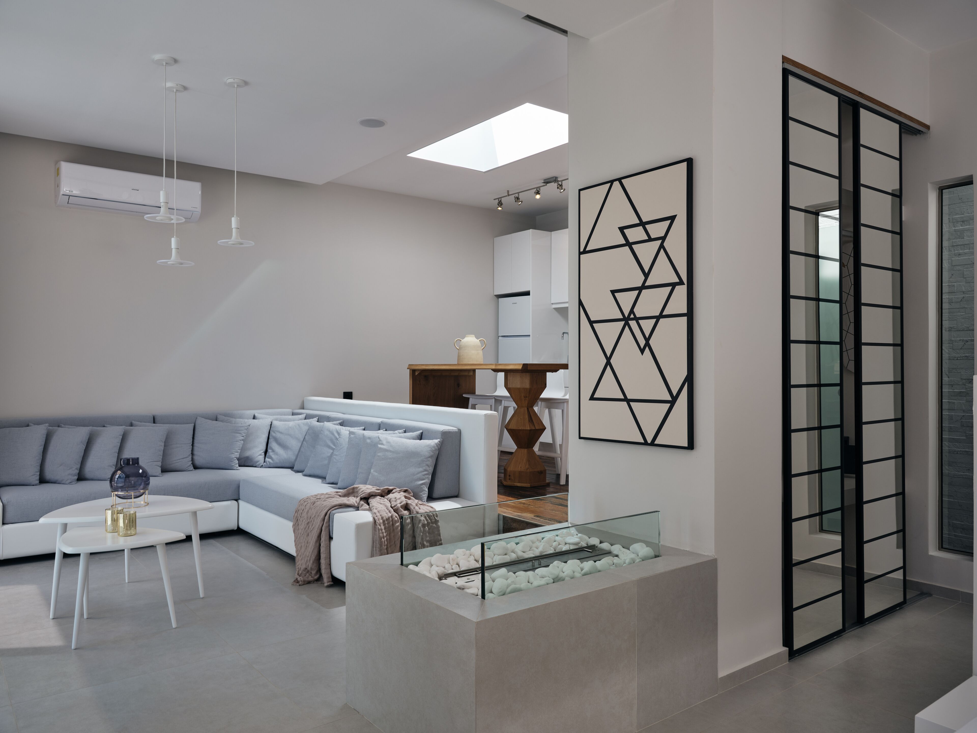 Una sala de estar moderna con un sofá modular gris, una mesa de centro de vidrio y un diseño minimalista.