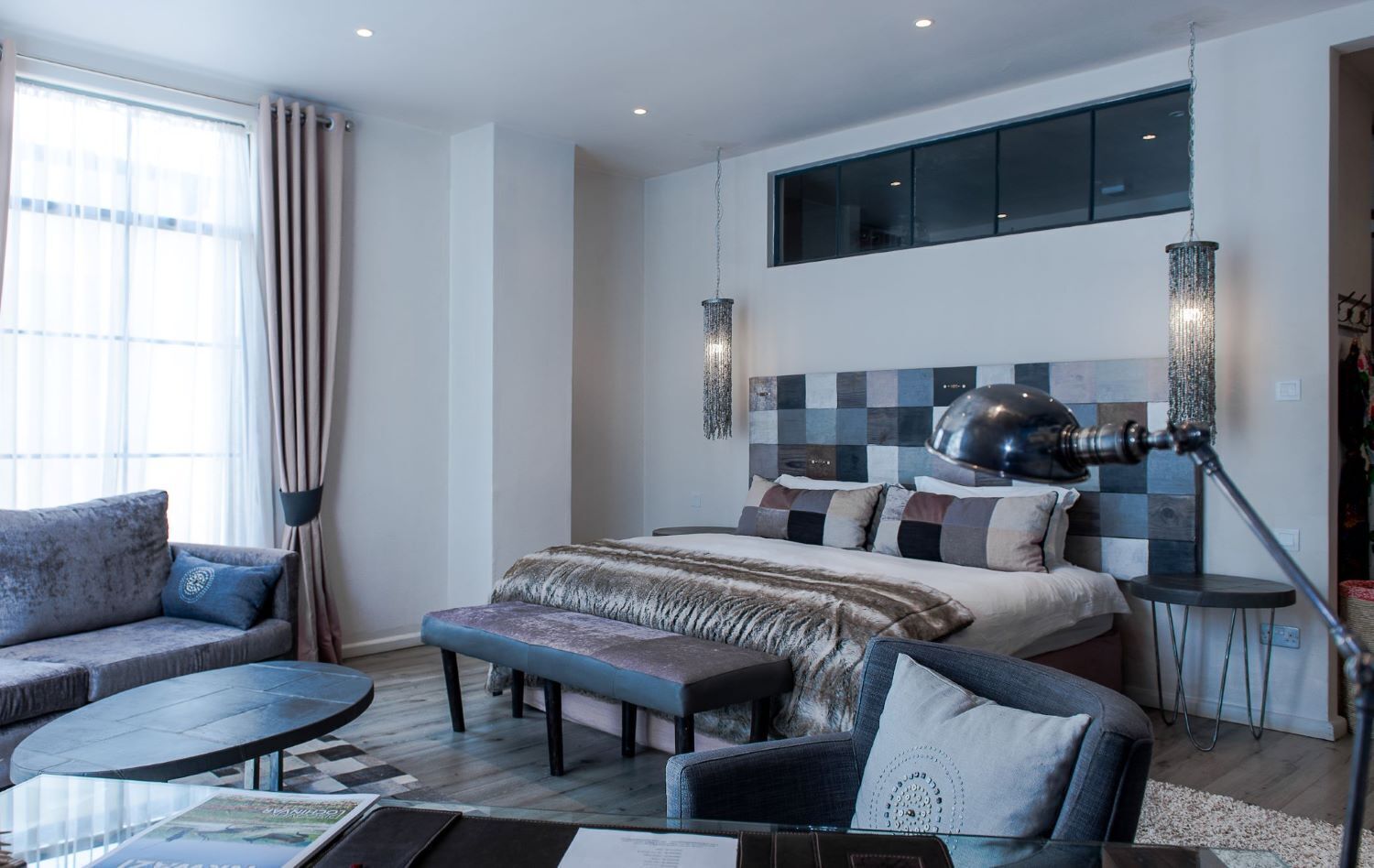 Una habitación de hotel moderna con una cama grande, un sofá, una mesita redonda y un escritorio.