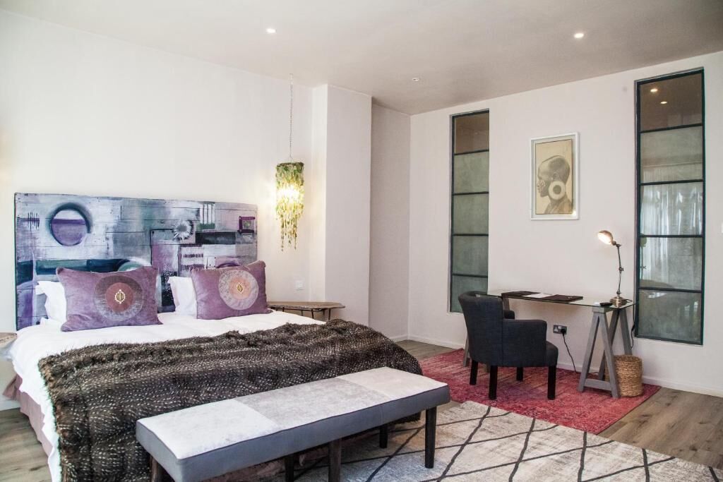 A modern bedroom with a large bed, a desk, and a chair.