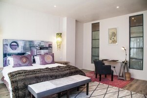 A modern bedroom with a large bed, a desk, and a chair.