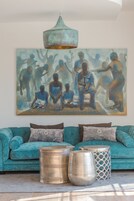Un sofá azul turquesa con dos cojines, una mesita auxiliar de metal y una mesa de centro de metal.