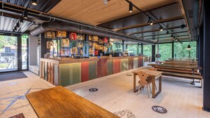 A modern bar area with a wooden counter, seating, and large windows.