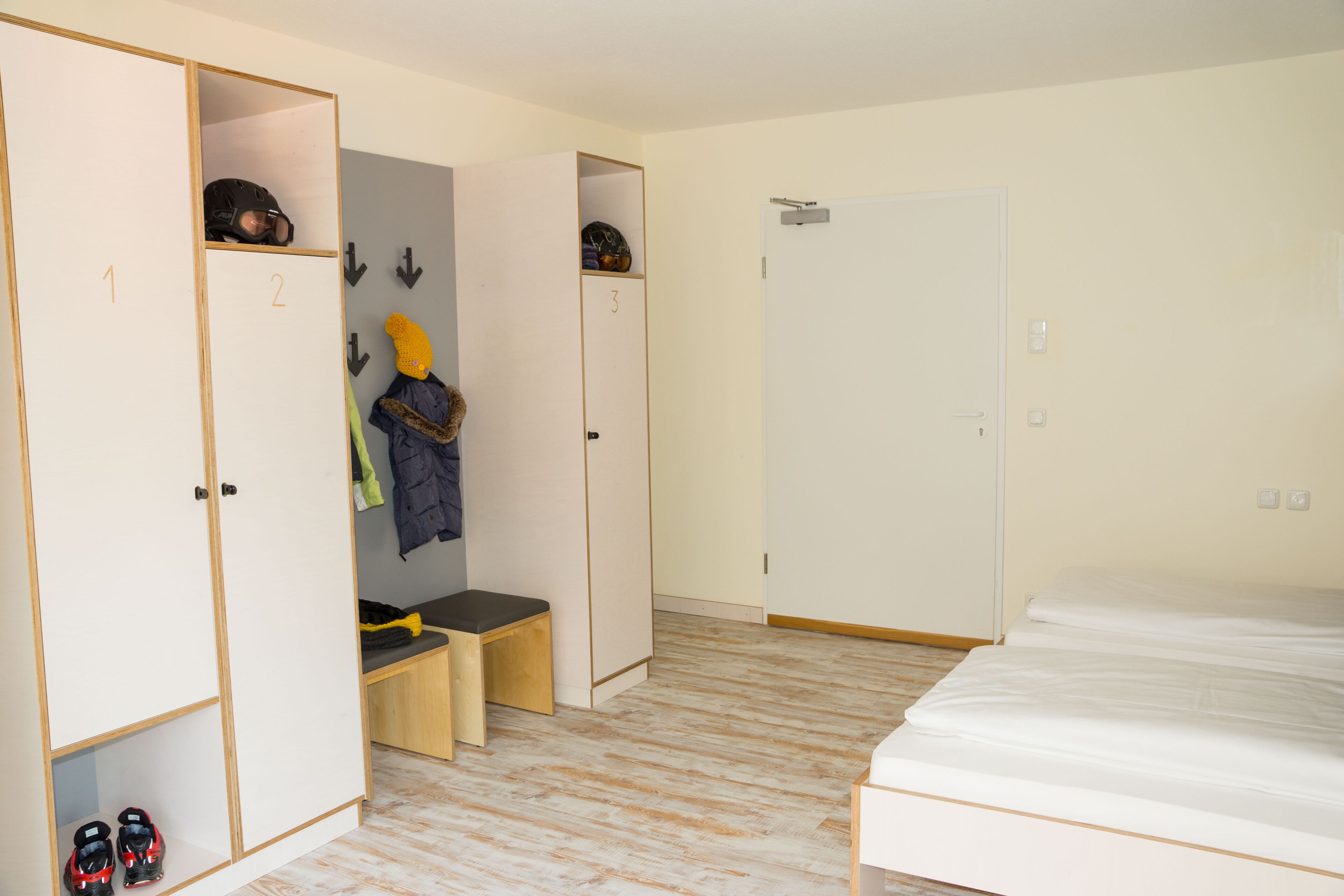 Una habitación con cama, armario, banco y puerta.