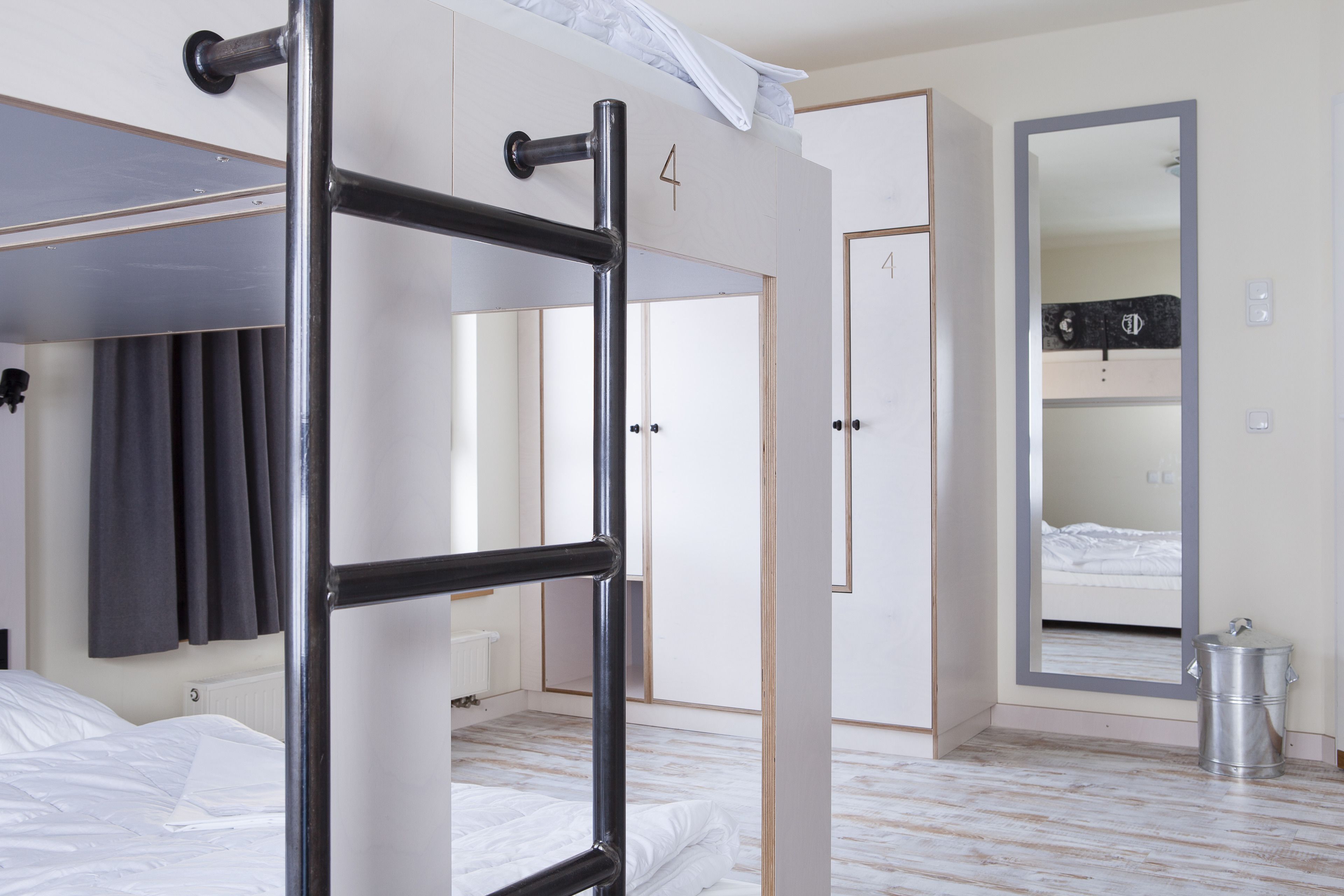 A hotel room with a bunk bed, a wardrobe, a mirror, and a radiator.