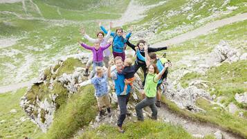 A group of people on a rocky mountain path with a view of a green valley.