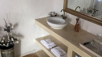 A bathroom with a white sink, a mirror with a gold frame, a towel rack, and a small white cabinet.