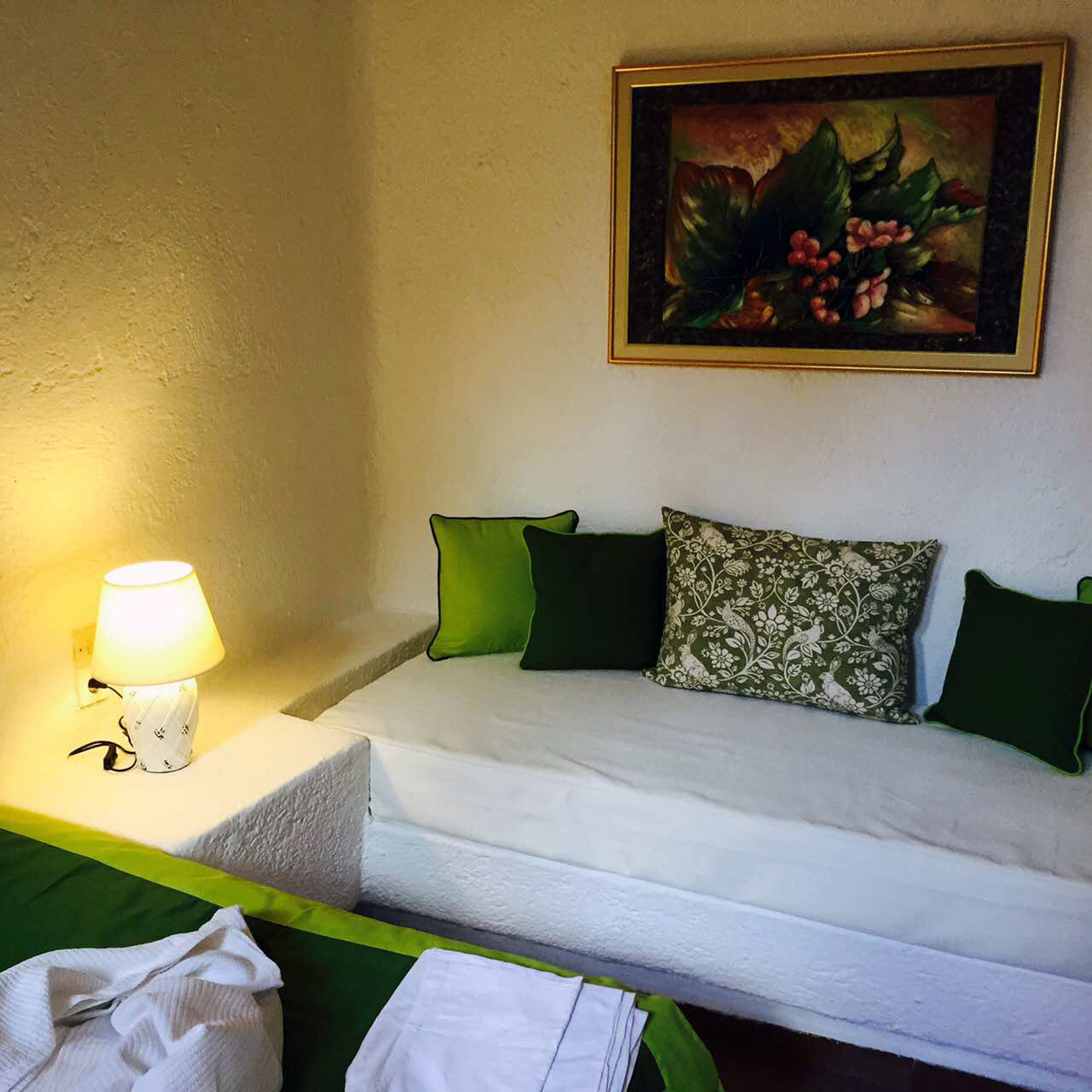 Een hotelkamer met een bed, een nachtkastje met een lamp en een schilderij aan de muur.