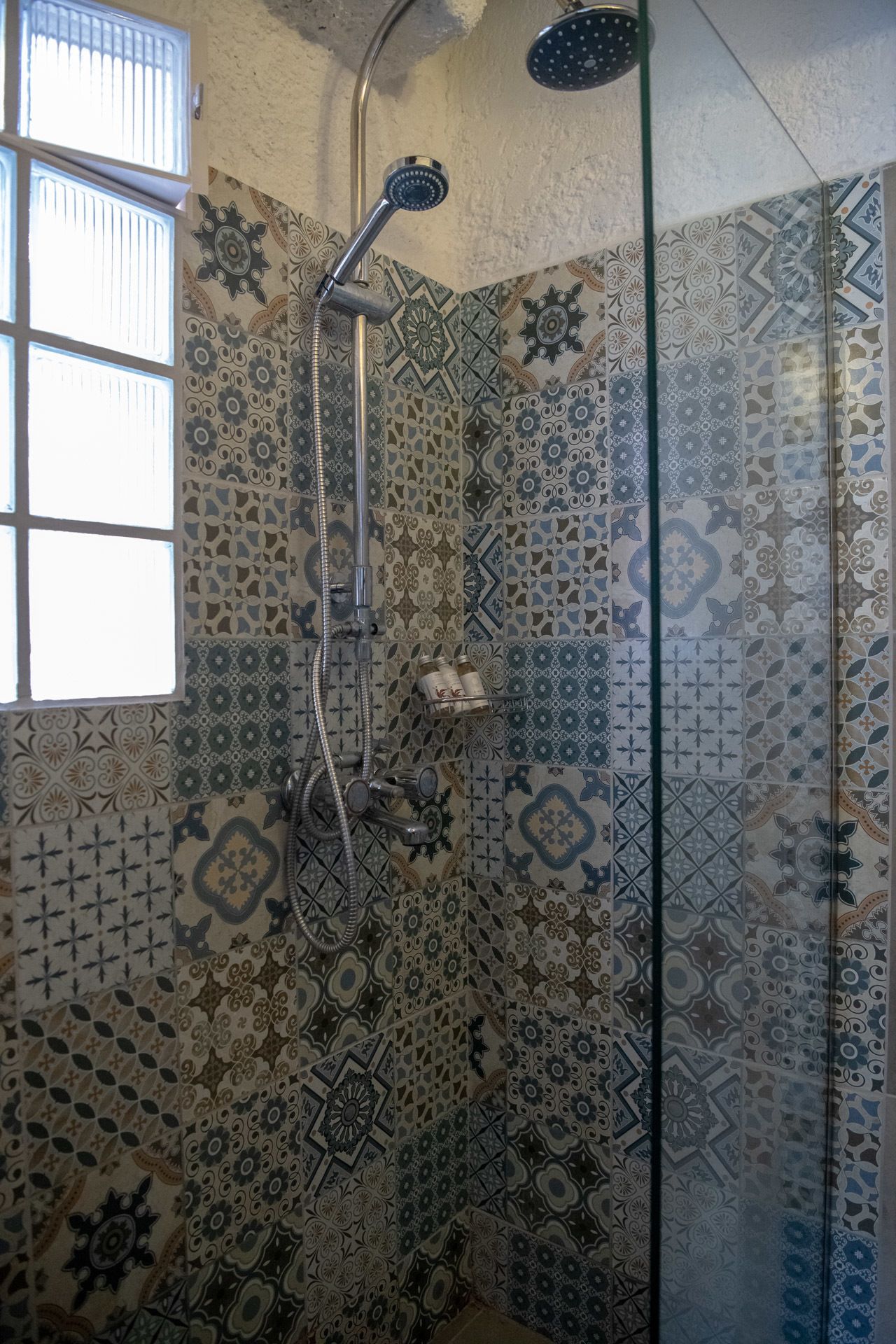 Una ducha con puerta de vidrio, cabezal de ducha de mano y grifo empotrado.