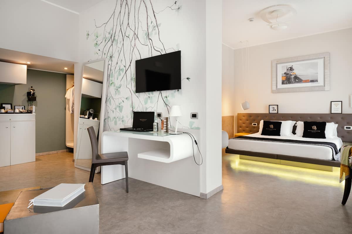 Una habitación de hotel moderna con escritorio, cama, televisor y un cuadro en la pared.