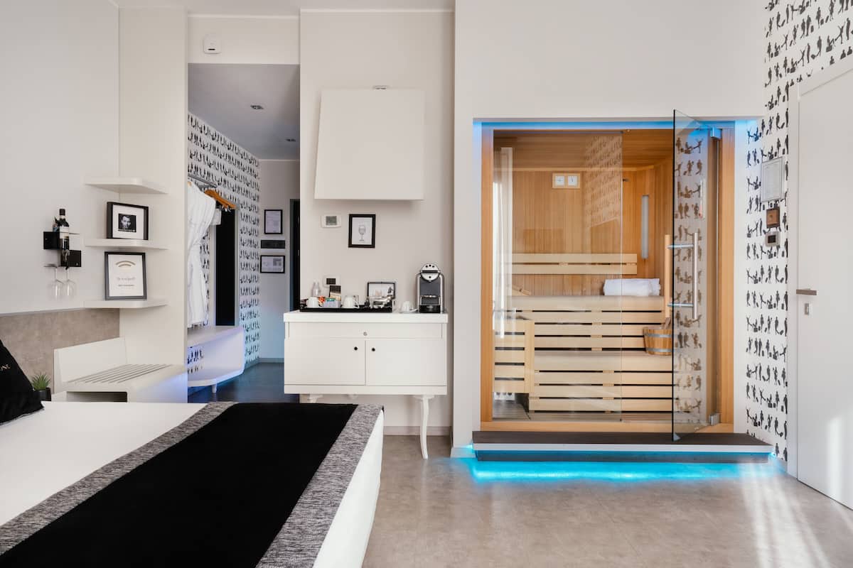 Una habitación de hotel moderna con cama, escritorio, baño pequeño y zona de sauna.