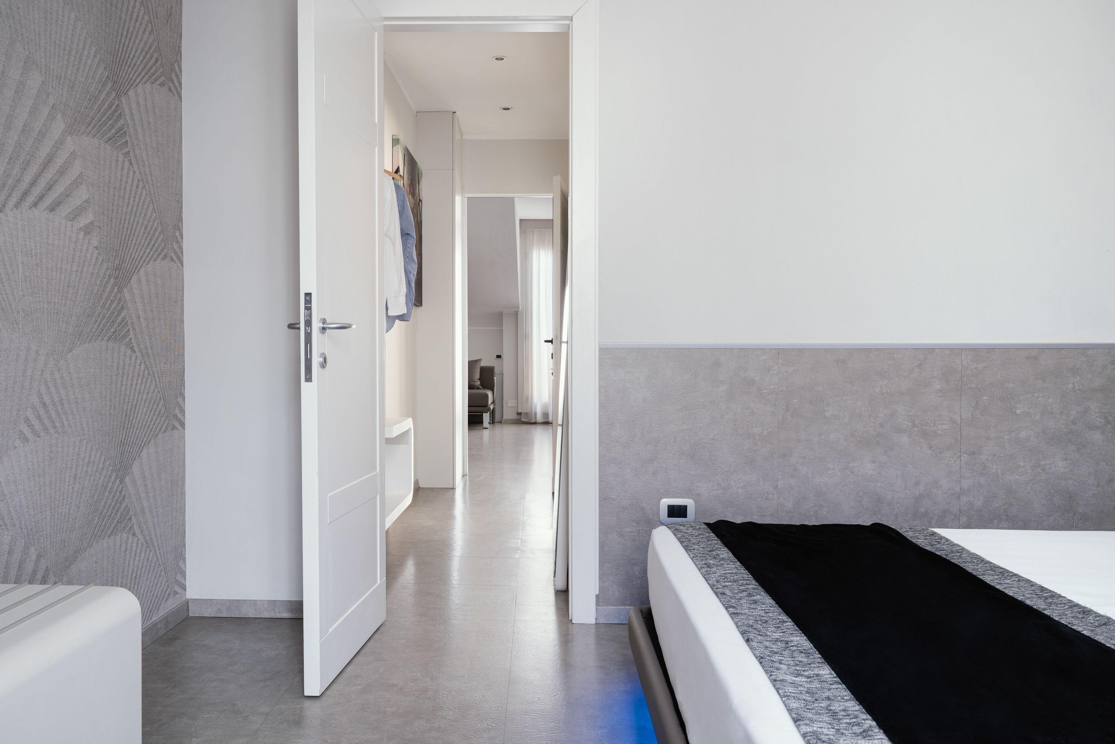Et moderne hotelværelse med en seng, et garderobeskab og en gang, der fører til et andet værelse.