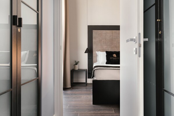 Een moderne hotelkamer met een bed, nachtkastje, lamp en een kleine bloempot.