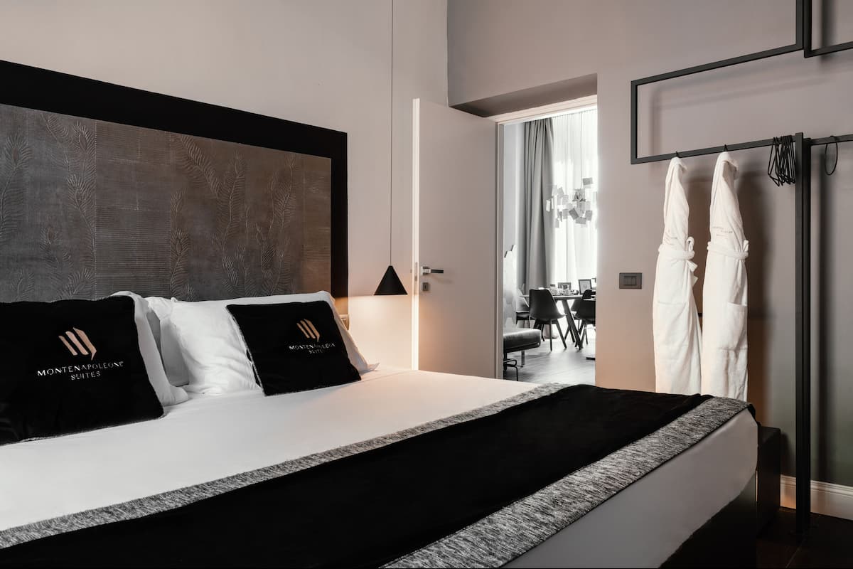 Una habitación de hotel moderna con una cama grande, un cabecero con diseño de hojas y vista al área de comedor.