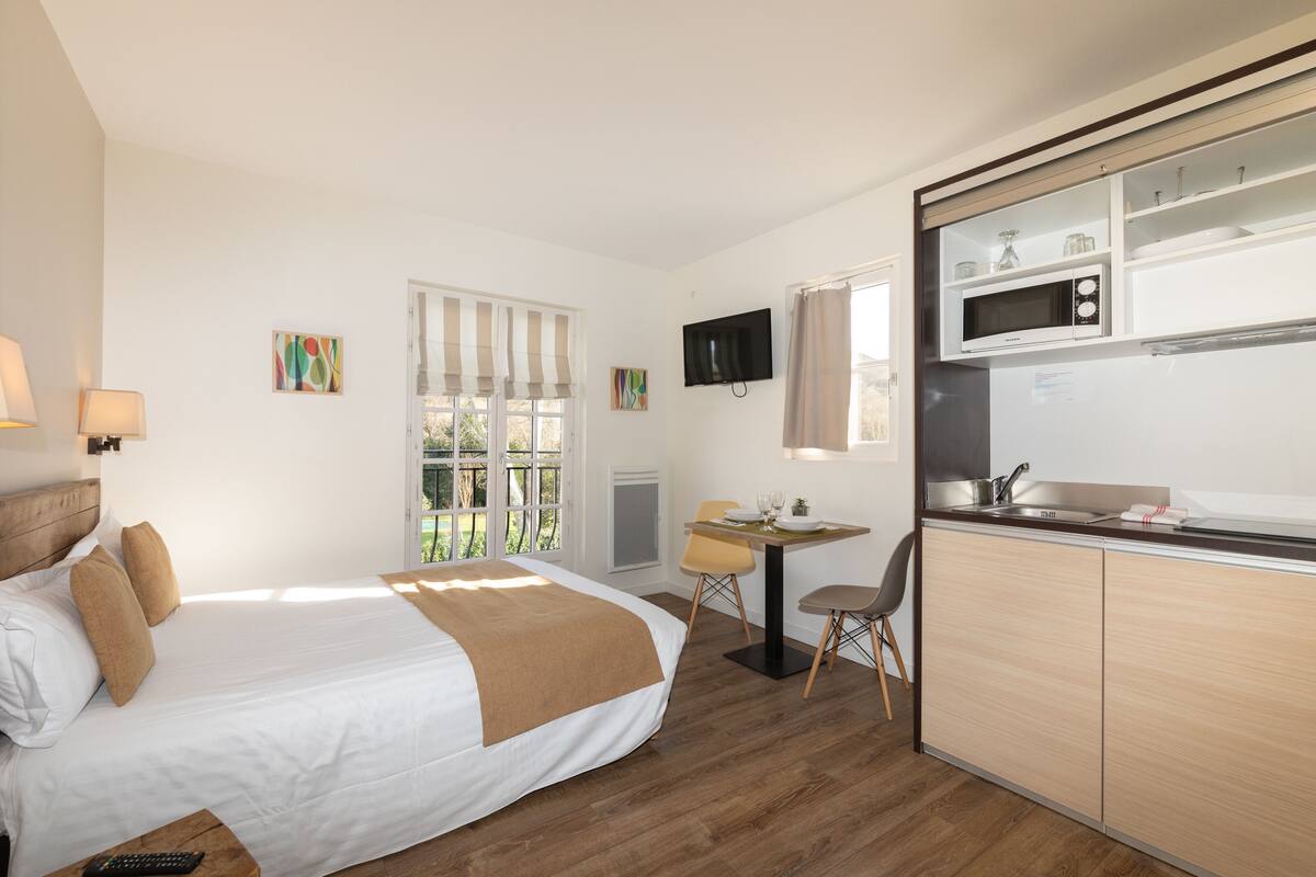A hotel room with a bed, a desk with a chair, a microwave, and a TV.