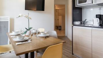 Una cocina moderna con microondas, pileta y cafetera negra. Hay una mesa de comedor con sillas y un florero.