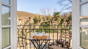 A balcony with a table set for two, overlooking a mountainous landscape. - Hôtel-Résidence Alaia (Ascain)