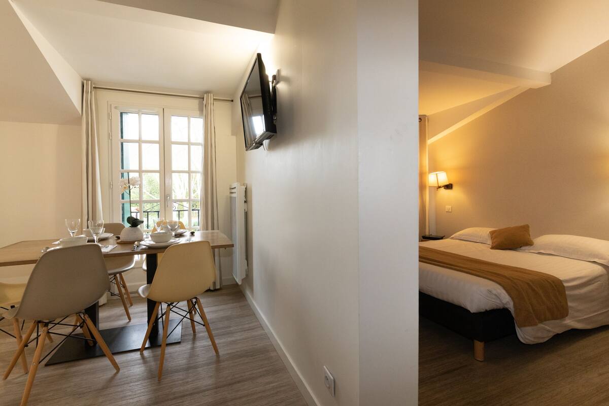 A hotel room with a bed, bedside table, lamp, and a TV mounted on the wall.