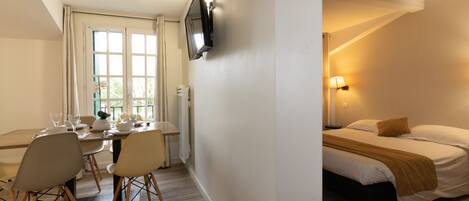 Habitación de hotel con cama, mesita de noche, lámpara y televisor montado en la pared.