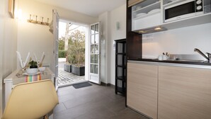 A modern kitchen with a built-in microwave, a sink, and a dining area with a chair and table. - Hôtel-Résidence Alaia (Ascain)