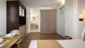 Habitación de hotel con cama, un escritorio de madera con silla, armario y baño a la vista.
