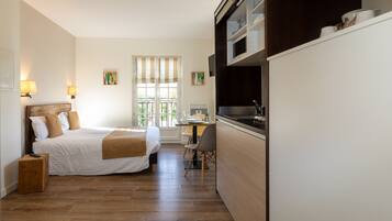 Een kleine slaapkamer met een bed, nachtkastje en een bureau met stoel.