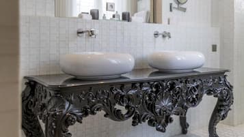 A bathroom with two white sinks, a large mirror, and a decorative black console table.