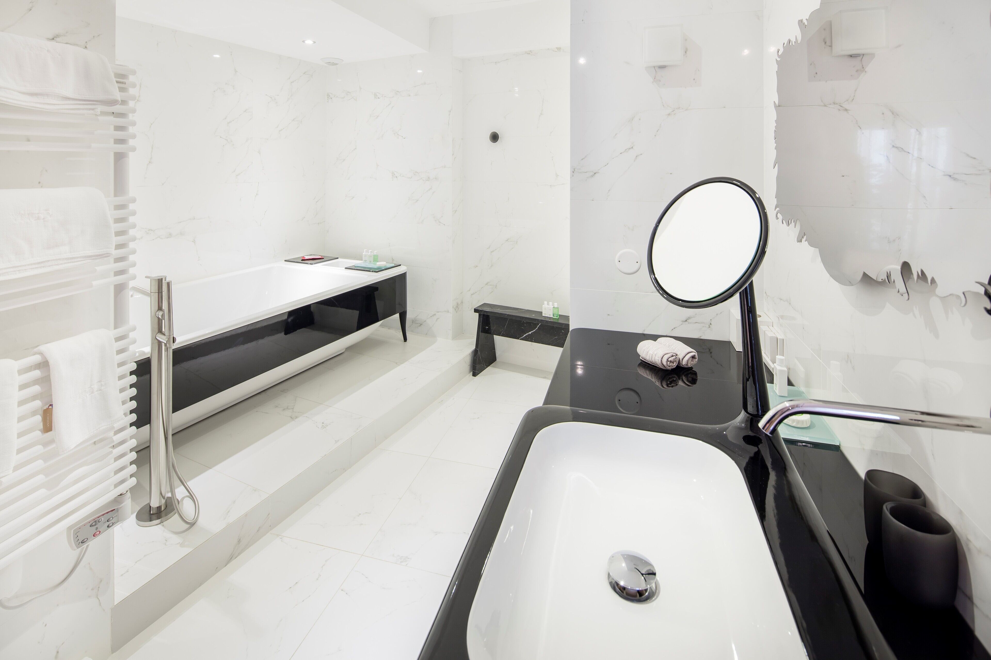 A modern bathroom with a large bathtub, a vanity with a mirror, and a towel rack.