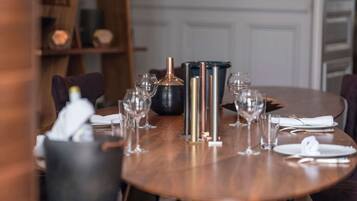 Une table à manger dressée avec plusieurs verres à vin, une bouteille et un vase noir.
