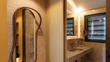 A bathroom with a marble floor, a wooden-framed mirror, and a window with blinds.
