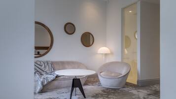 Un salon moderne avec une table ronde, un canapé, un fauteuil et trois miroirs fixés au mur.